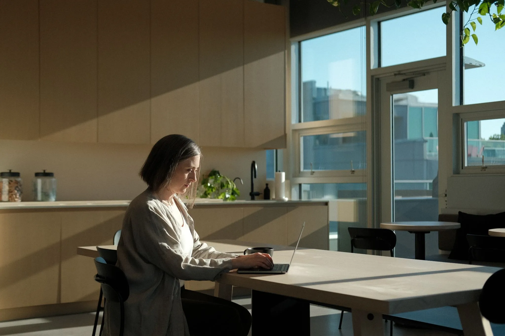 Rebecca Sorbara working on laptop in modern workspace with city view