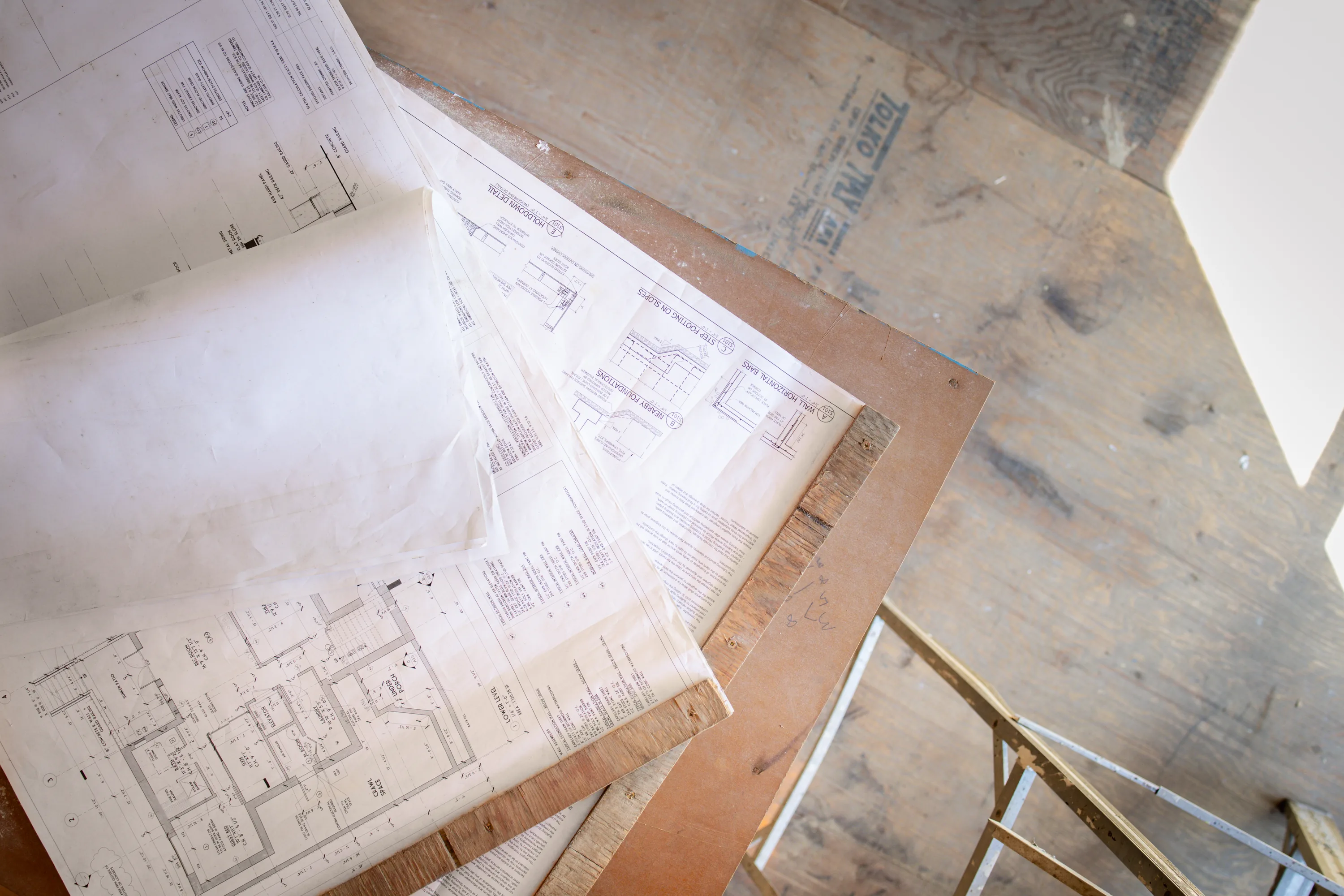 Architectural blueprints spread out beside a staircase in a home under construction