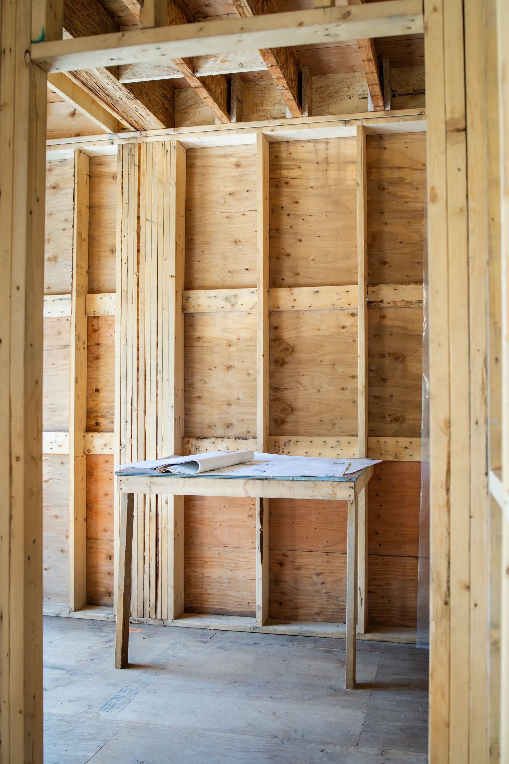 Interior of an empty wood-framed home with blueprints on a worktable, residential construction in Vancouver
