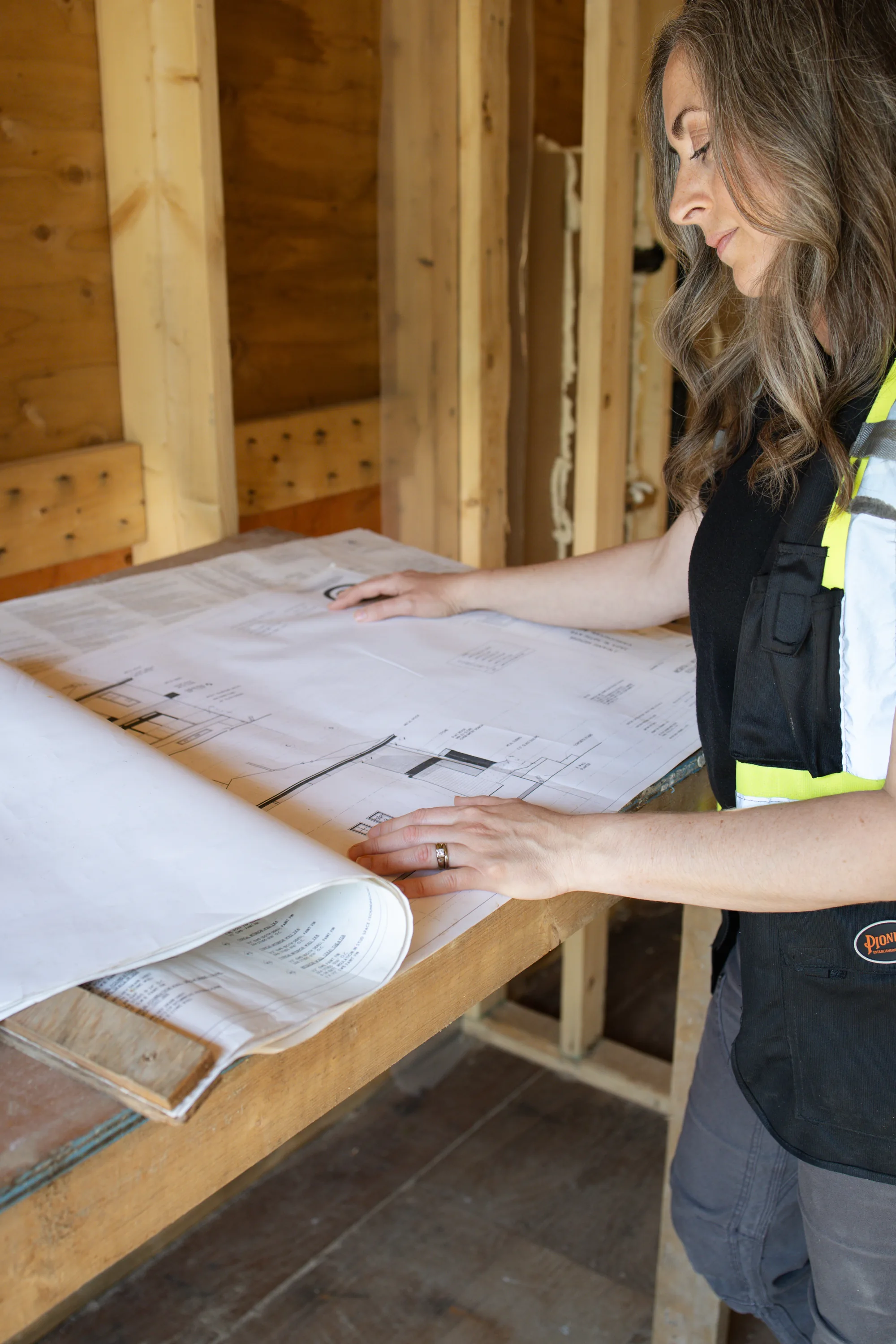 Rebecca Sorbara examining architectural building plans at a residential construction site