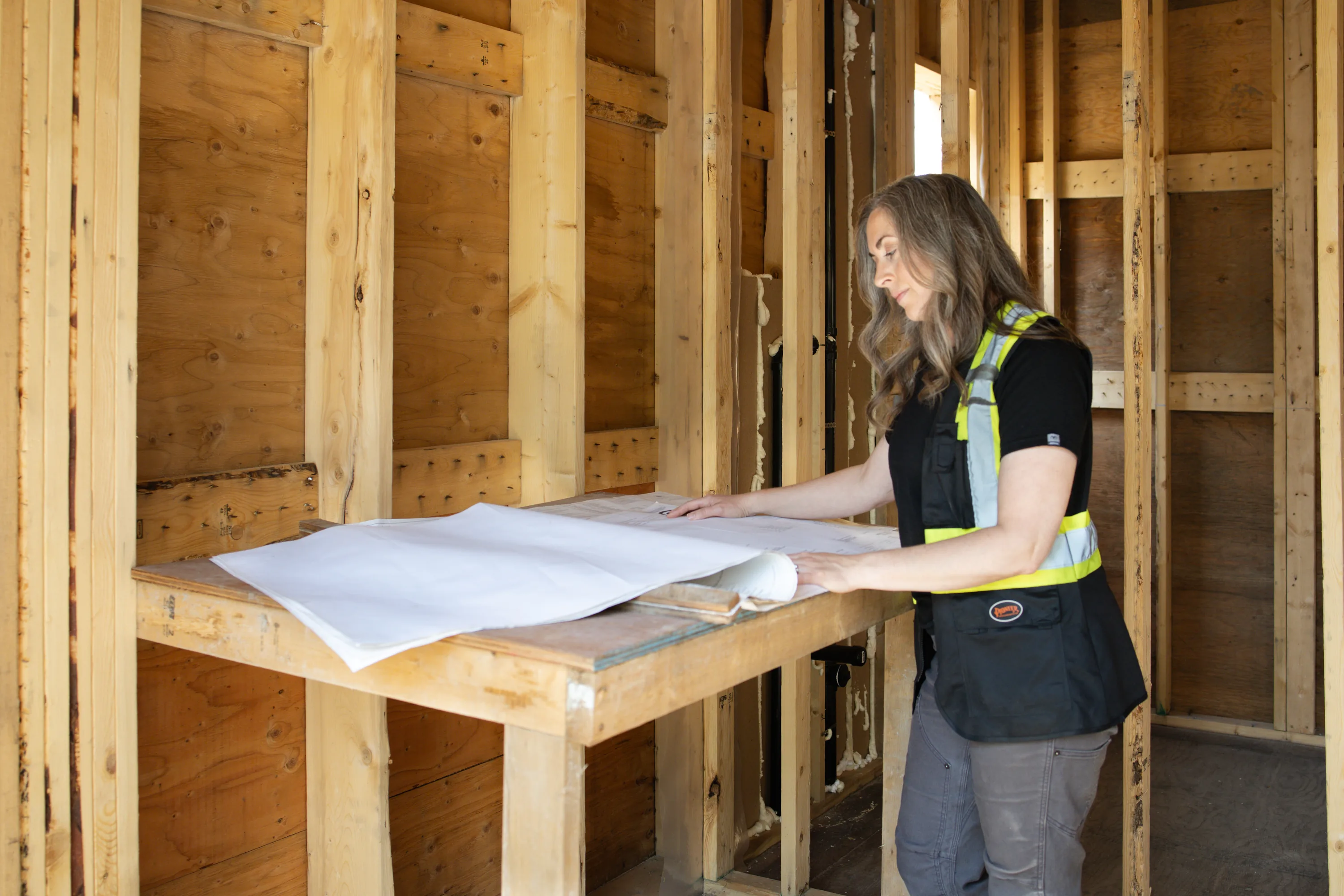 Rebecca Sorbara reviewing architectural blueprints inside a wood-framed home at a Vancouver residential building site