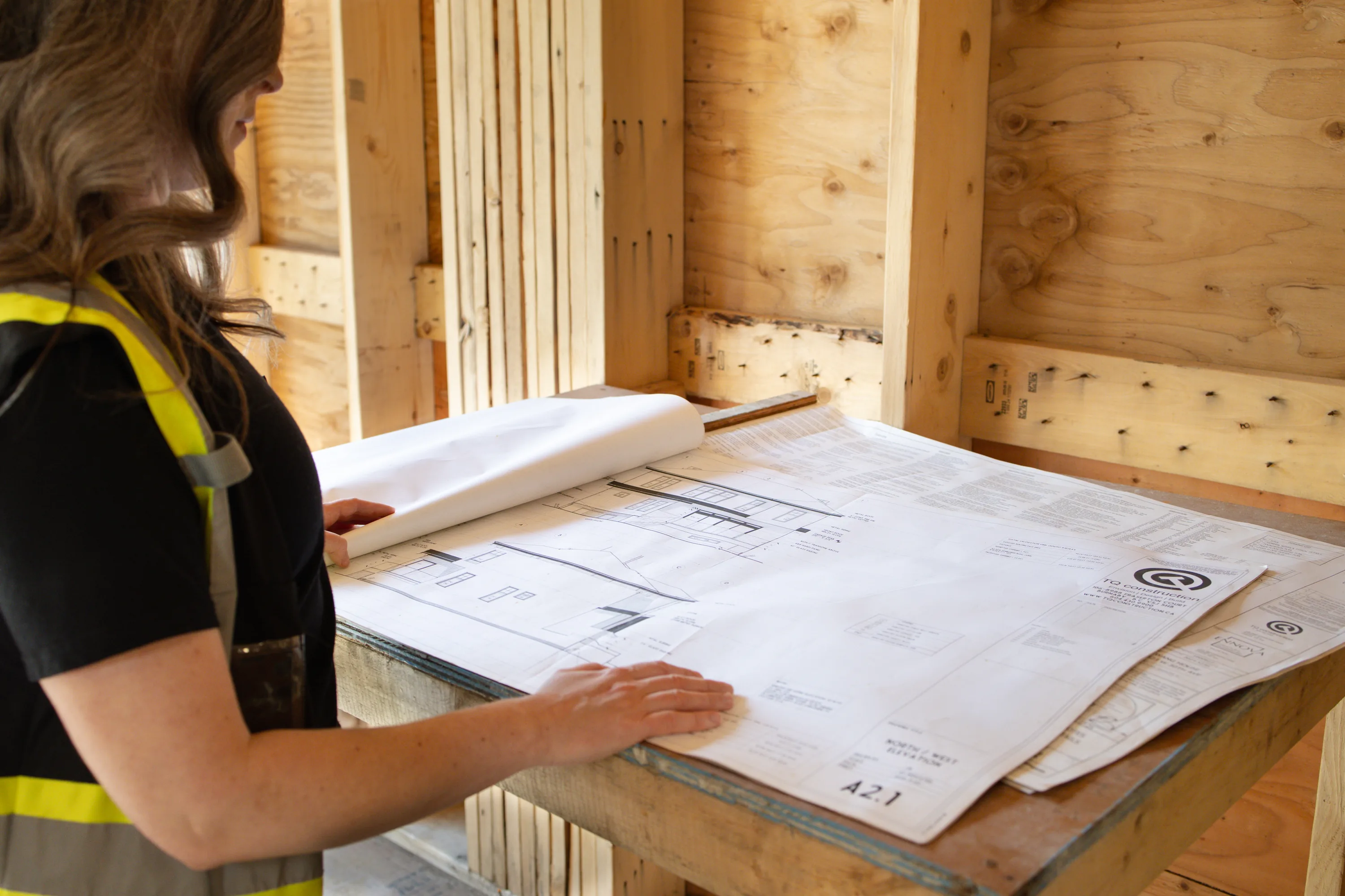 Rebecca Sorbara reviewing permit drawings at a worktable on a residential job site